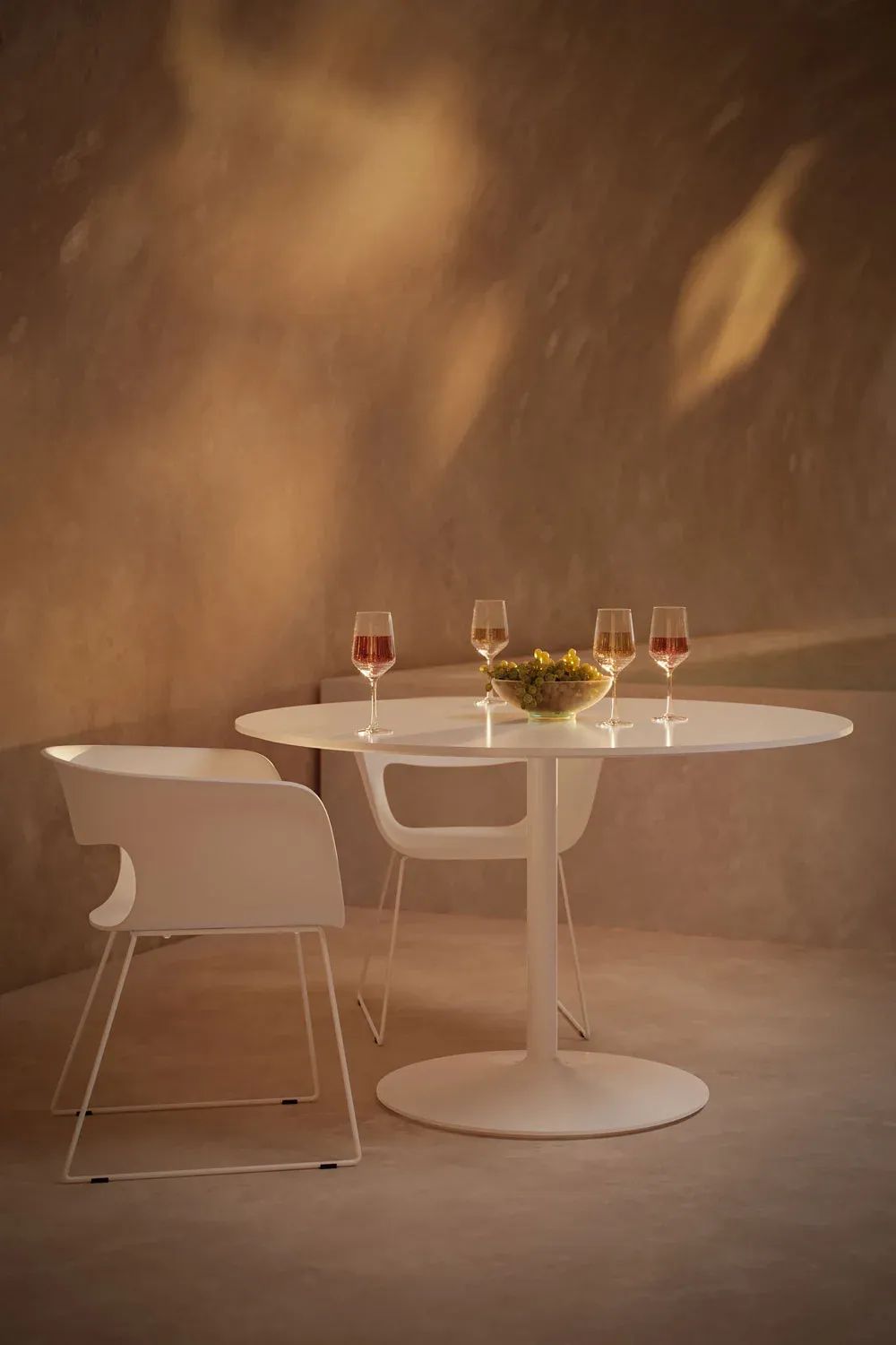 Product render for catalogs showing a round white dining table with modern chairs and wine glasses on top